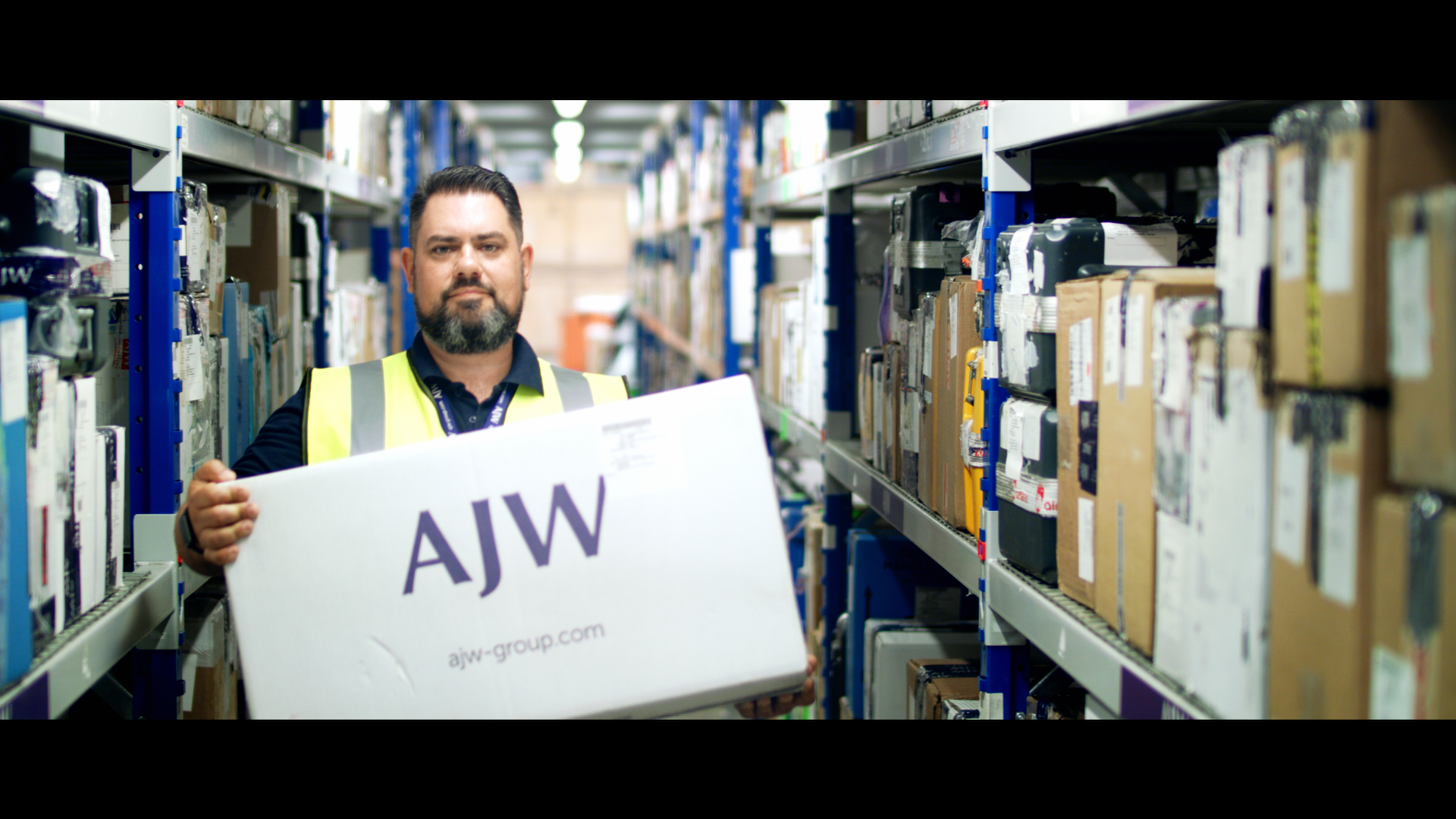 AJW Group employee carrying branded box in factory