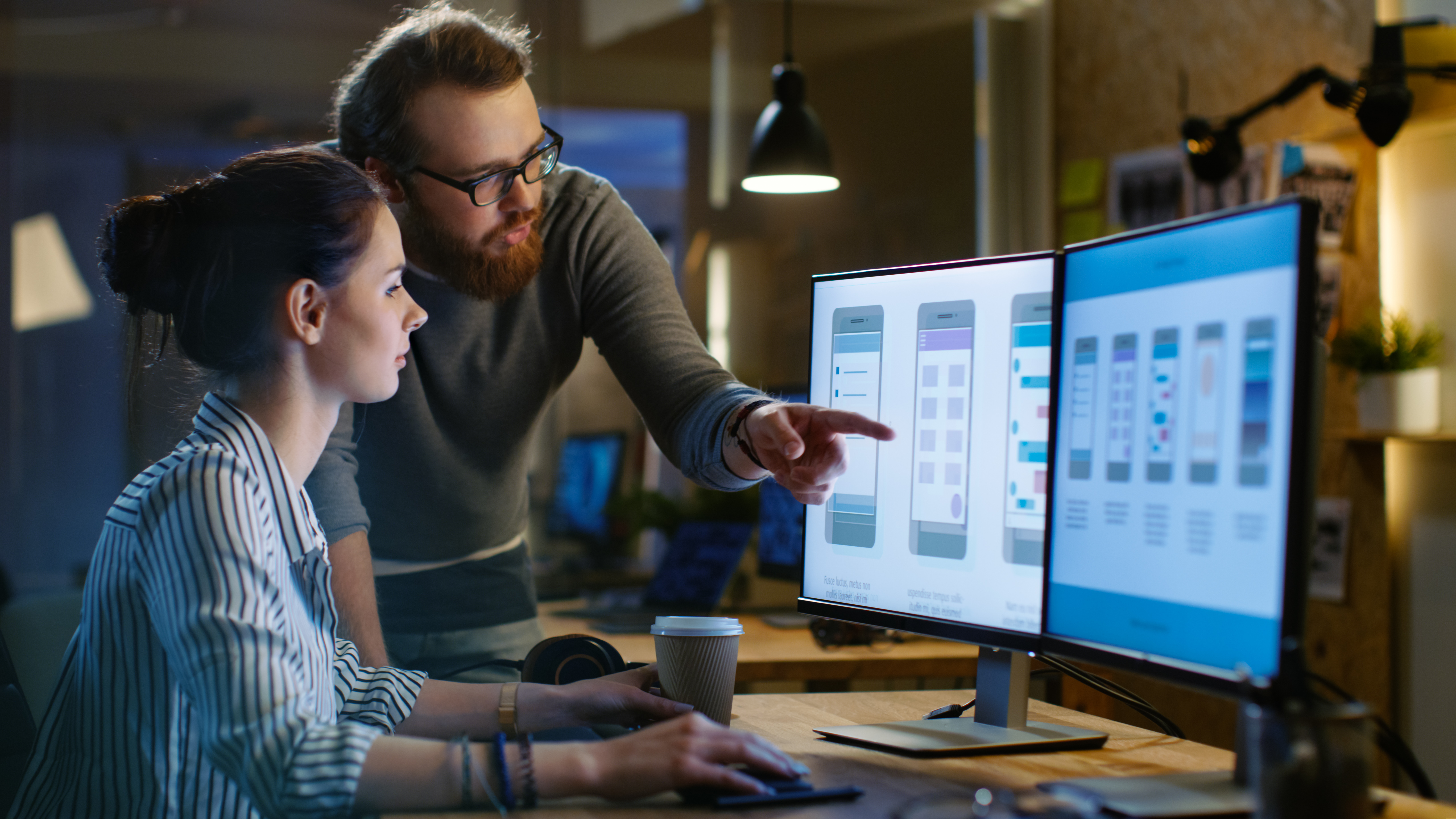 Man pointing to computer screen to show woman something